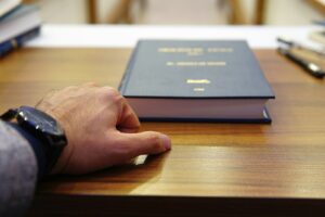 personne tenant un livre à couverture noire sur une table en bois marron