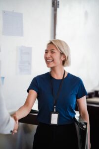 Une femme d'affaires sympathique en chemise bleue serre la main lors d'une réunion, rayonnant de professionnalisme et d'accessibilité.