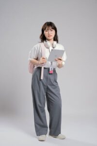 Jeune femme confiante avec des écouteurs tenant une tablette, prête à étudier ou à travailler.