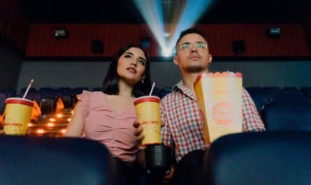 2 women sitting on blue leather chair holding white and red plastic cups