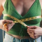 Woman measuring her bust with a tape measure