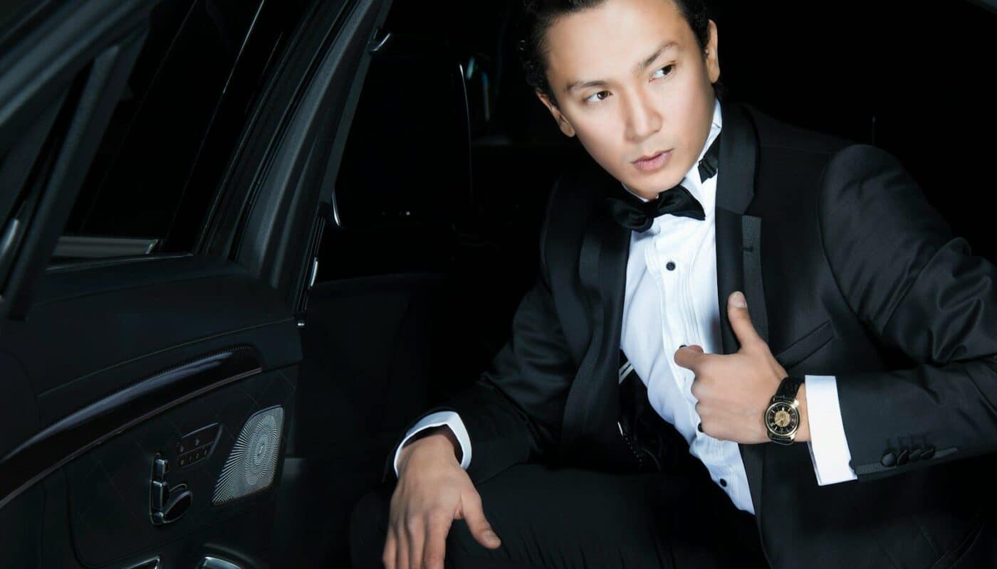 man in black blazer sits inside the car
