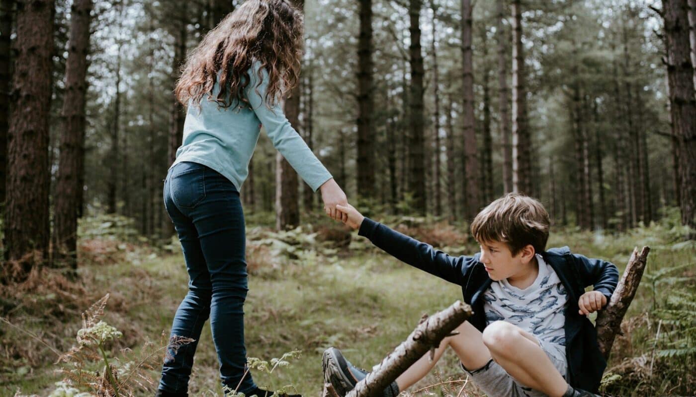 boy and girl playing on three tree log