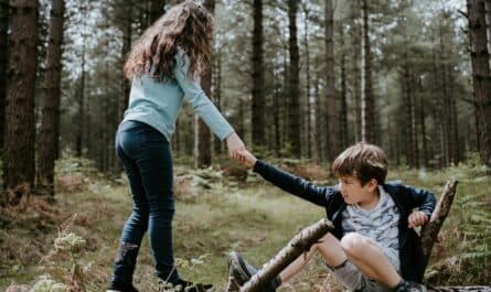 boy and girl playing on three tree log