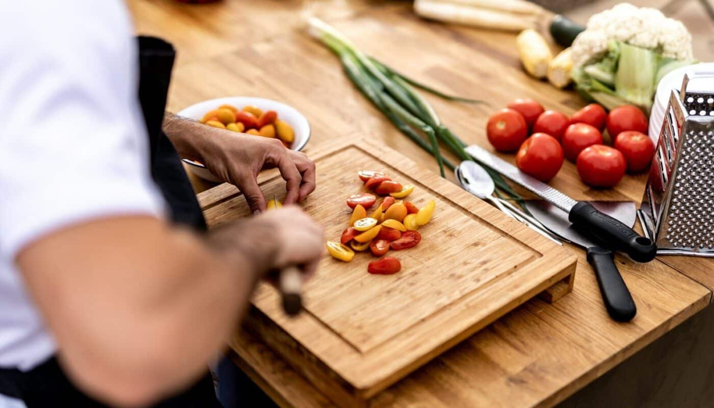 a person cutting up vegetables on a cutting board