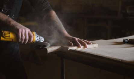 Personne utilisant une lime électrique sur une planche en bois dans un atelier