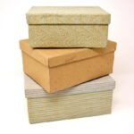 Trois boîtes de rangement en carton et tissu sur fond blanc