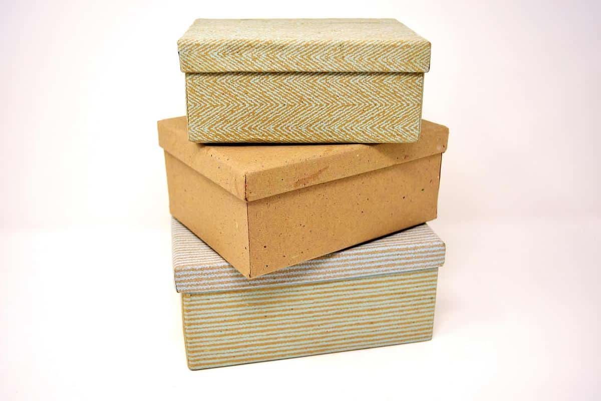 Trois boîtes de rangement en carton et tissu sur fond blanc