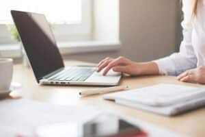 Femme travaillant sur ordinateur portable avec stylo et cahier à côté