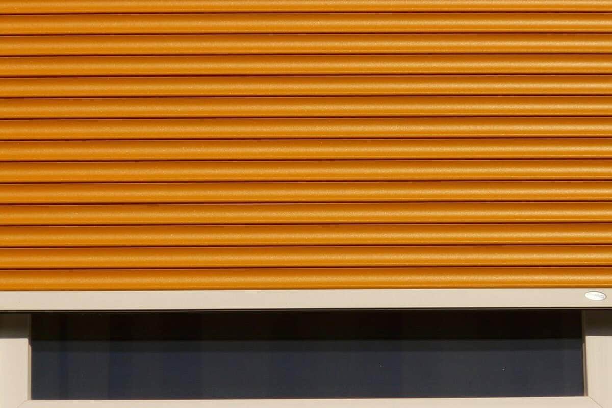 Volet roulant orange fermé sur une fenêtre avec cadre blanc