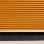 Volet roulant orange fermé sur une fenêtre avec cadre blanc