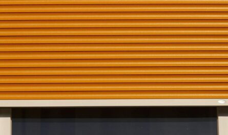 Volet roulant orange fermé sur une fenêtre avec cadre blanc