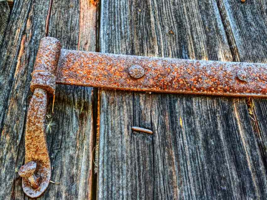 Hingé rouillé fixé sur planches de bois usées, aucune activité visible