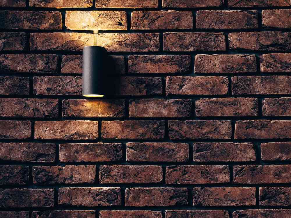 Lampe murale noir sur mur de briques, lumière chaude
