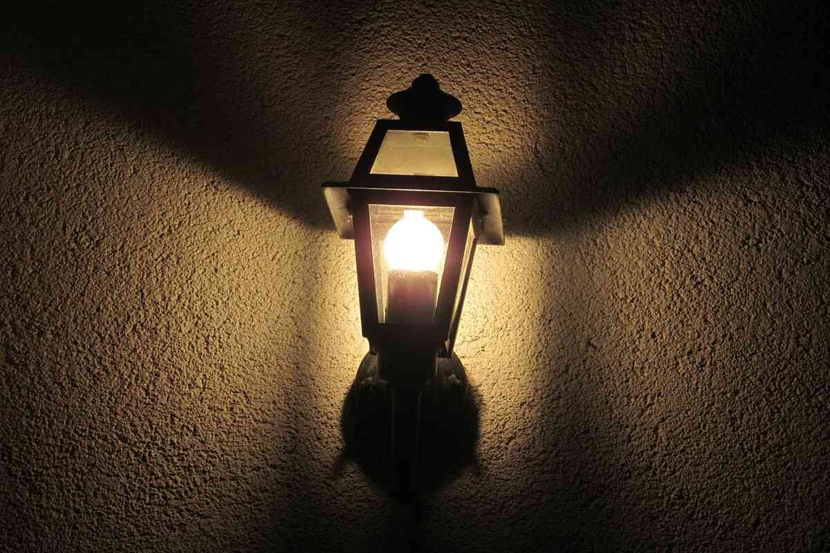 Lampe de jardin vintage éclaire le mur sombre avec une lueur chaude
