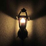 Lampe de jardin vintage éclaire le mur sombre avec une lueur chaude